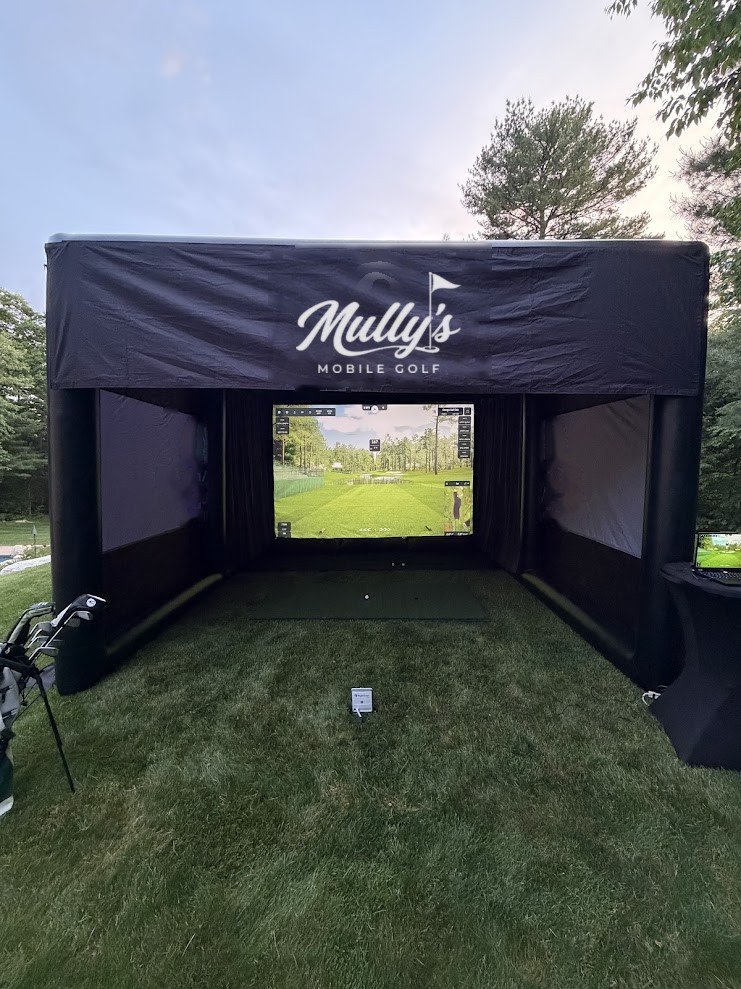 The Mully's golf simulator enclosure set up on a lawn, screen showing a fairway
